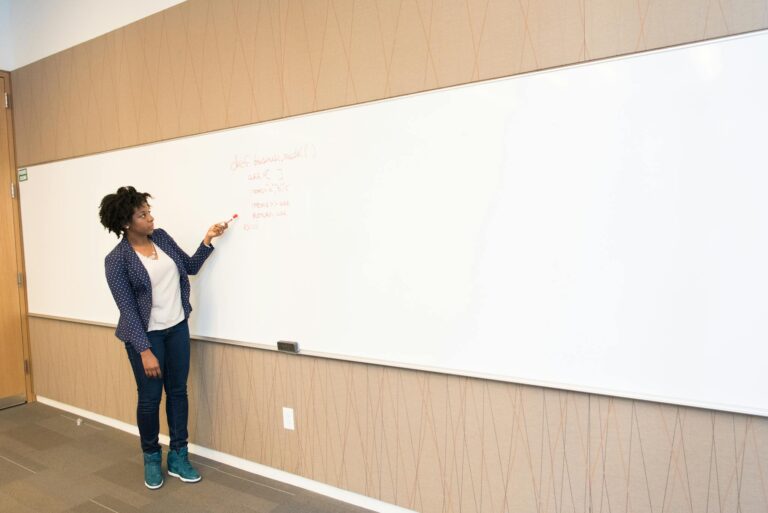 Woman Wearing Black Blazer Holding Pen Pointing White Marker Board